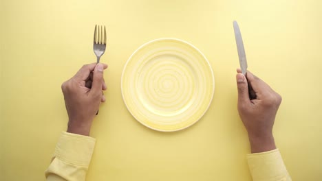 empty plate with cutlery on yellow background