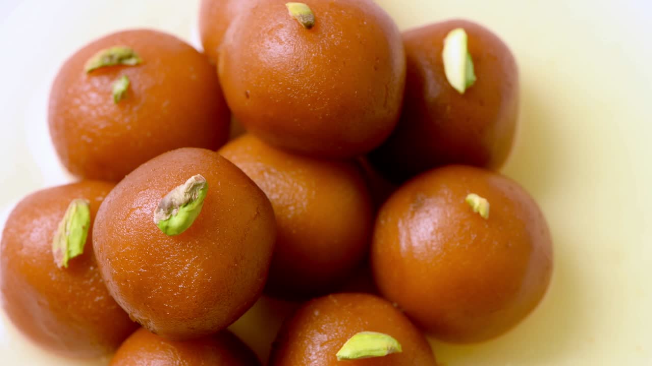 Gulab jamun rotante con granella di pistacchio (dolce indiano) | Dessert | Ripresa dall'alto e primo piano