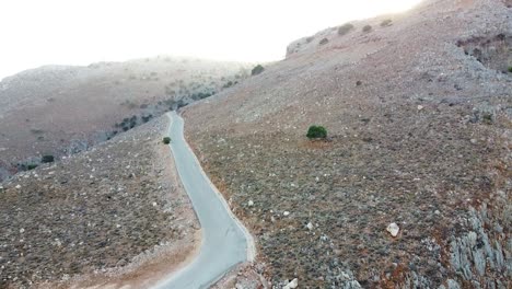 winding asphalt road leading to seitan limania, aerial ascend view