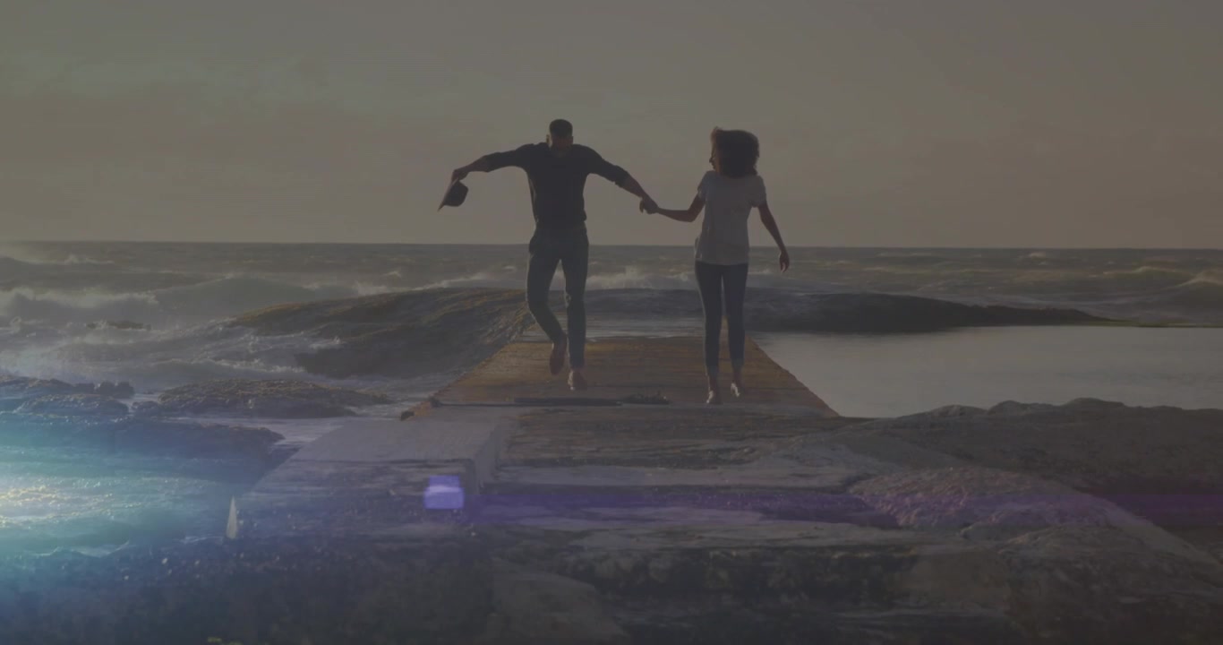 Animazione di un punto luce su una coppia afroamericana che cammina sugli scogli vicino al mare.