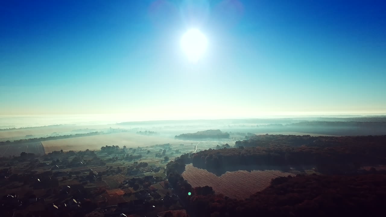 Morning sunrise in the village on misty weather. Panoramic view of beautiful dawn over the roofs of the houses and big forest. Aerial View. Soft sun light. Slow motion.