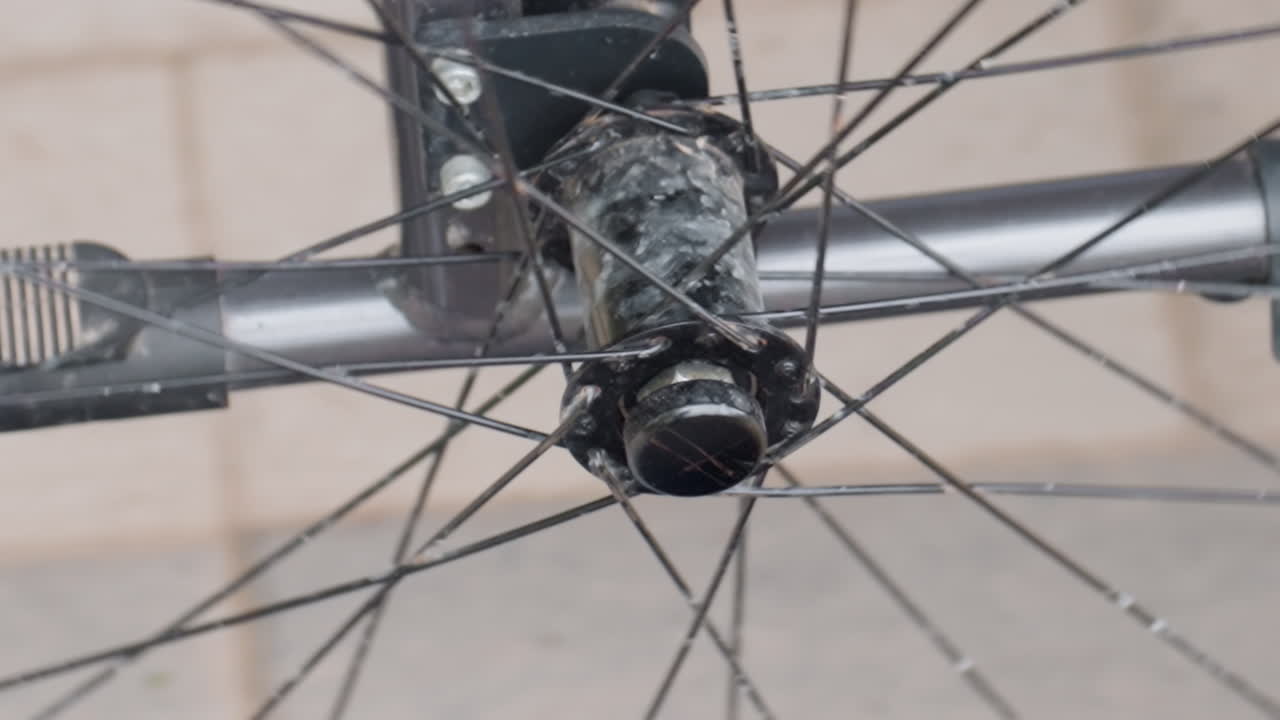 Close Up Wheelchair Wheel Hub Shows Corroded Axle And Worn Spokes Mobility Technician Inspects And Lubricates Bearing, Revealing Rusted Bolts, Grease Residue, Metal Texture And Urban Sidewalk