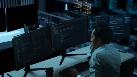 side view of bored asian man developer write code with multiple computer screens in the office