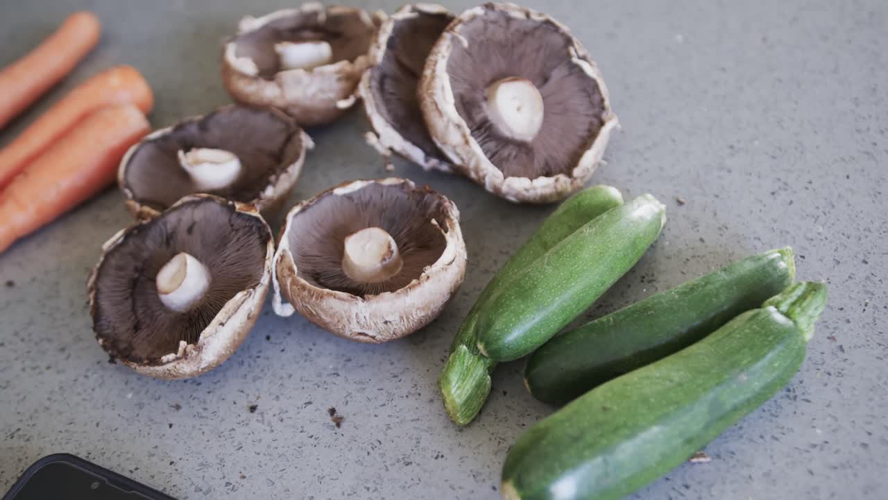 close up de albahacanes, hongos y zanahorias en la encimera gris en la cocina, cámara lenta