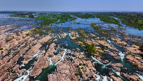 aerial view of the mekong river flowing through rocky rapids and lush green islets in don det, laos, illustrating the river’s powerful currents, scattered vegetation, and vast natural expanse
