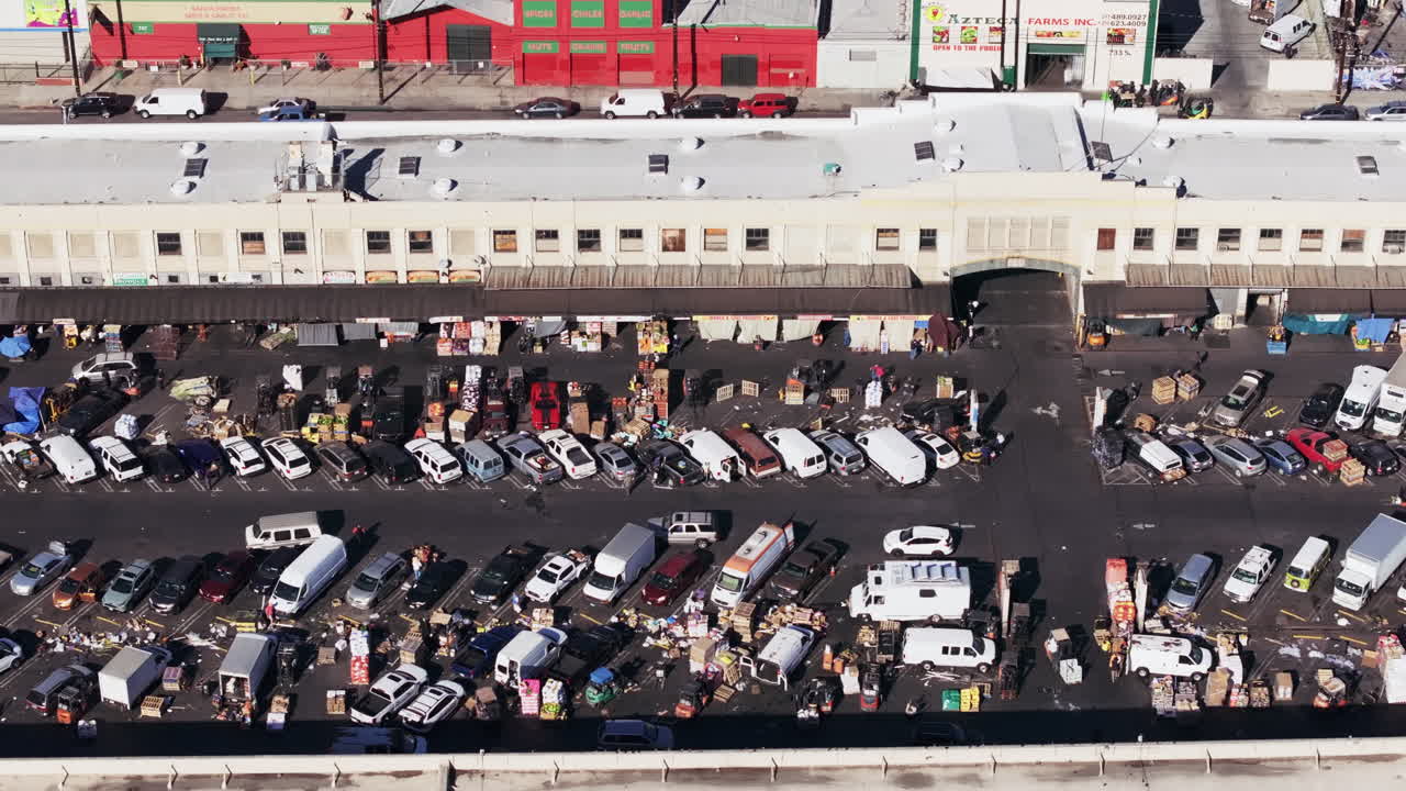 Aerial view of a bustling urban wholesale market with numerous trucks, vans, and goods