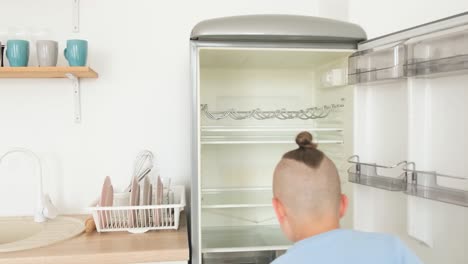 a little boy opens the refrigerator in the kitchen a hungry child is alone at home a little boy opens the refrigerator in the kitchen a hungry child is alone at home refrigerator without products