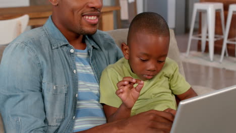 Padre-E-Hijo-Usando-Una-Computadora-Portátil-En-El-Sofá