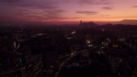 Panoramic-aerial-view-of-a-nostalgic-sunset-with-the-skyline-of-Santiago-Chile,-orange-and-purple-colors