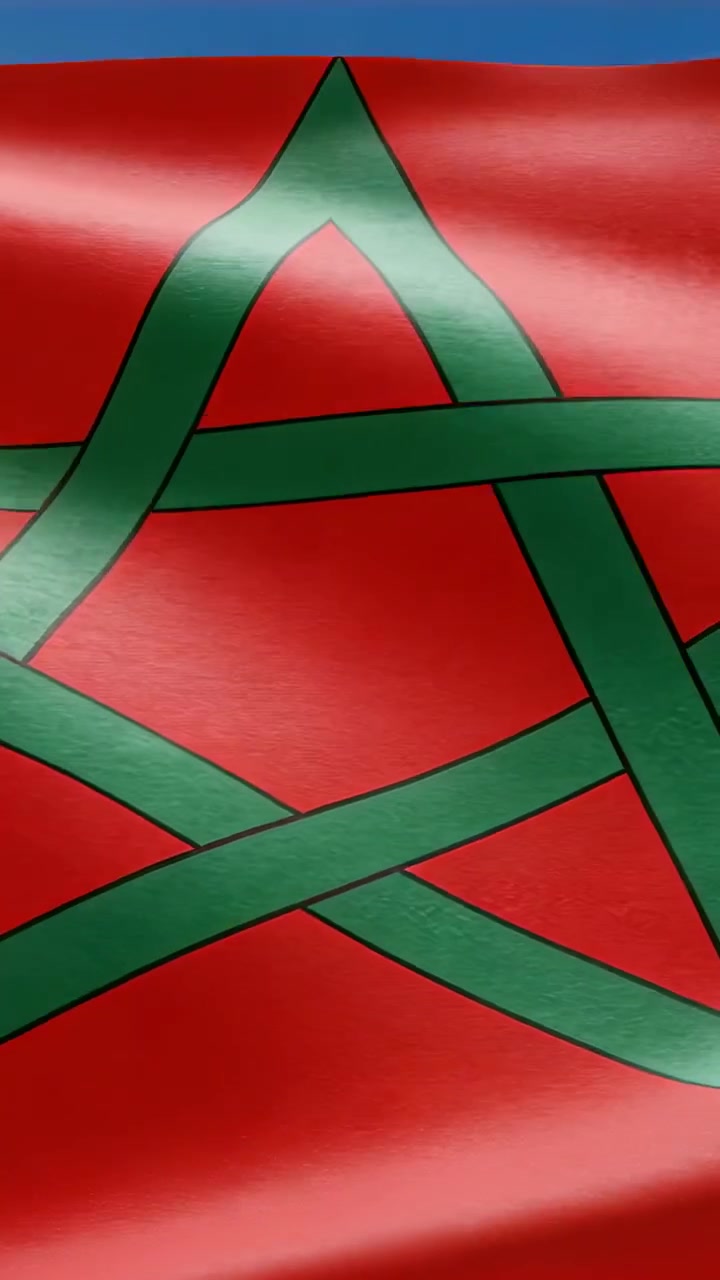 Video verticale: Tessuto rosso che sventola con un pentagramma verde, il vento che solleva i bordi rivelando il cielo blu.