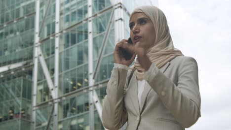 une femme d'affaires musulmane au téléphone portable debout devant un bureau dans la ville 4