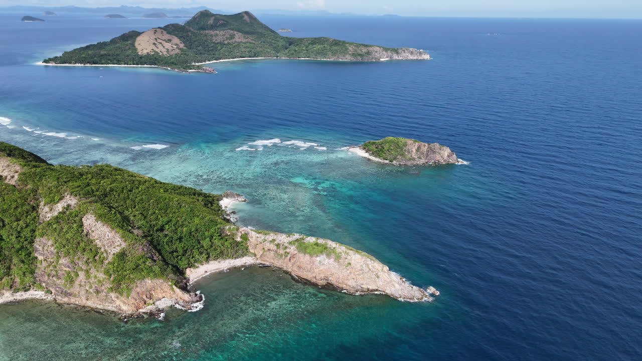 Ripresa con drone in allontanamento di un promontorio roccioso a Ile Island che rivela le isole vicine e acque turchesi che lambiscono le barriere coralline costiere.