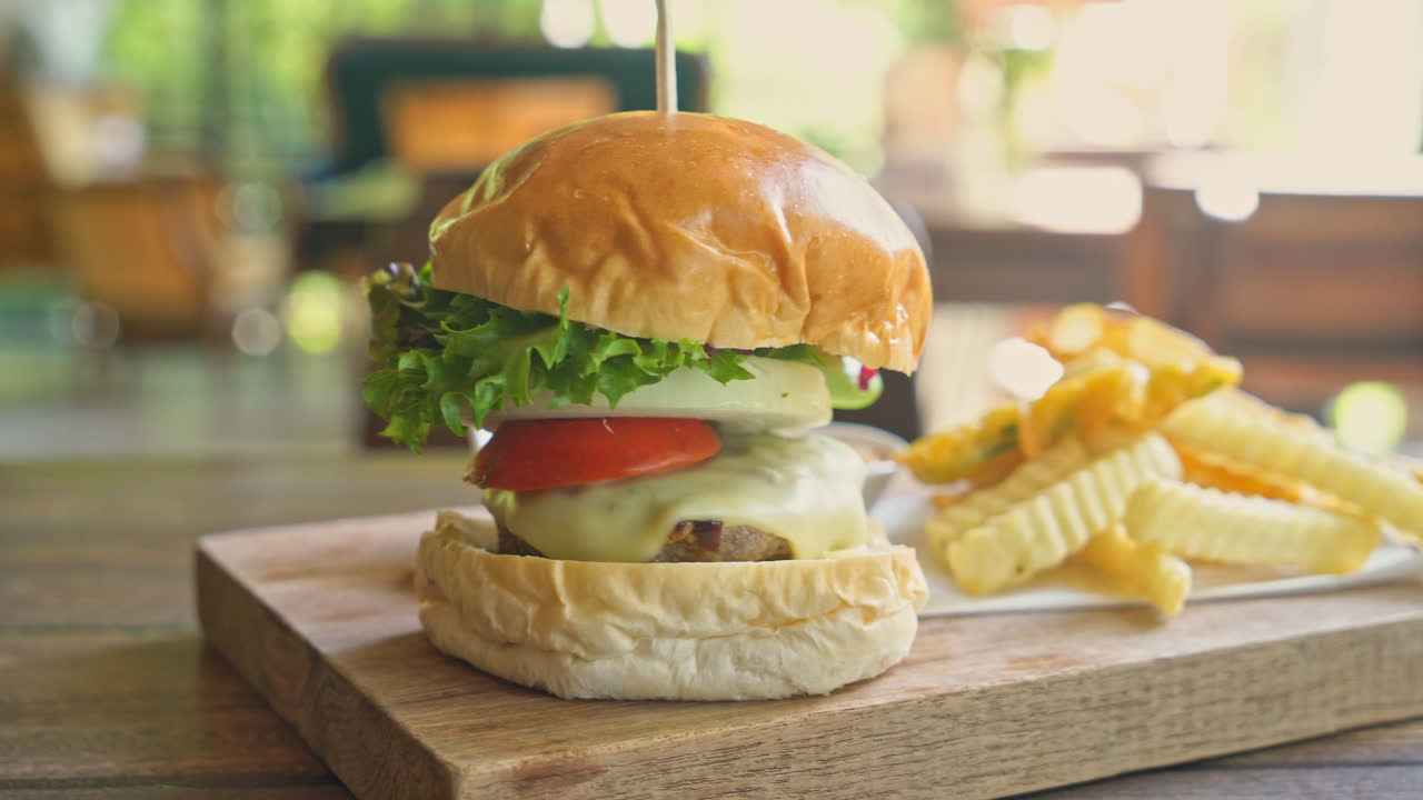 Hamburguesa de ternera con queso y patatas fritas en bandeja de madera