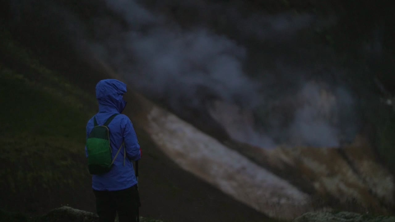 아이슬란드 풍경, 지열 온천 증기 연기, 연기가 피어오르는 것을 보는 한 사람, 카메라 기울기, 어둡고 변덕스러운 저녁 분위기