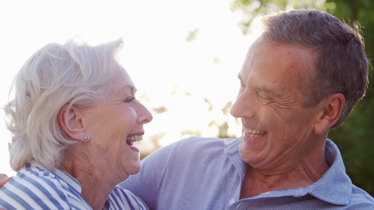 портрет улыбающейся старшей пары на открытом воздухе в летнем парке