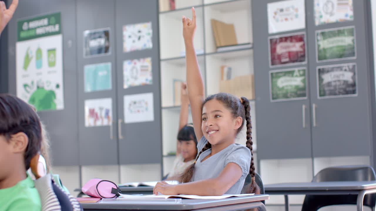 Biracial girl raises her hand in a classroom at school