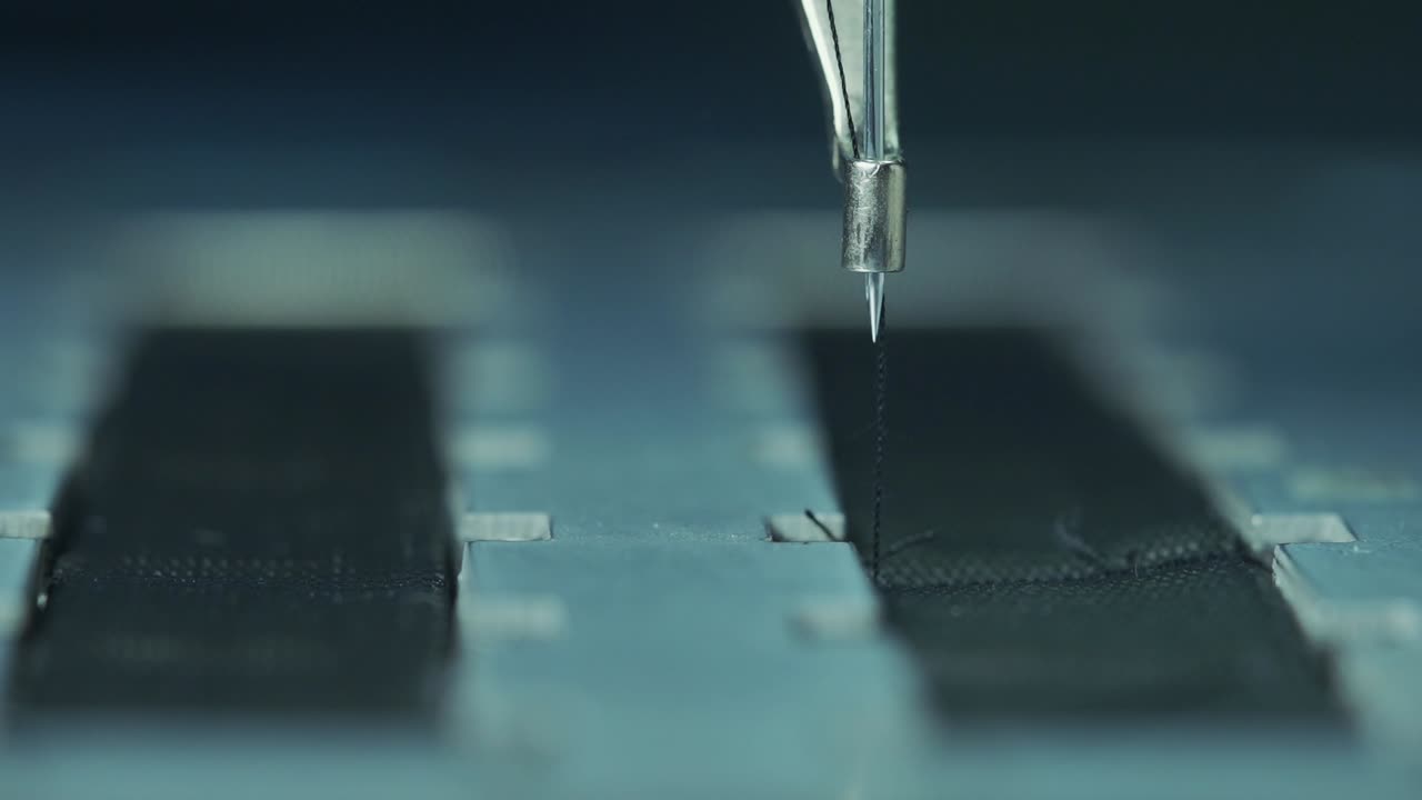 산업용 재봉틀은 검은 천을 꿰맨다. 확대