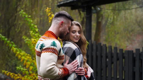young man hugged and covered girl with blanket. beautiful couple outside. autumn nature background.