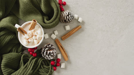 video of cup of hot chocolate with marshmallows and warm blanket over grey background