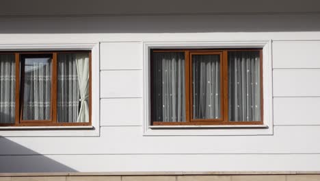 two windows with curtains on a white wall