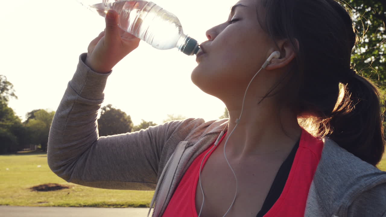 mujer de fitness bebiendo agua al aire libre en el parque