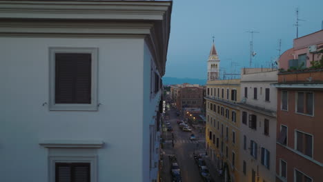 Wall-with-windows-in-facade-of-apartment-house-in-city.-Sliding-reveal-of-street-in-urban-borough-at-twilight.-Rome,-Italy