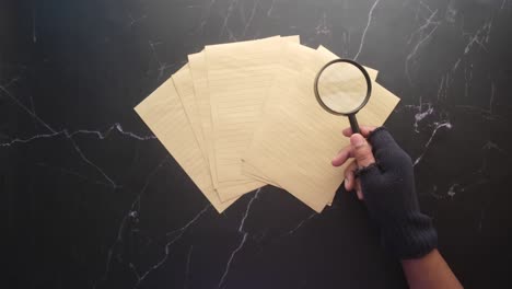 hand with magnifying glass examining old documents