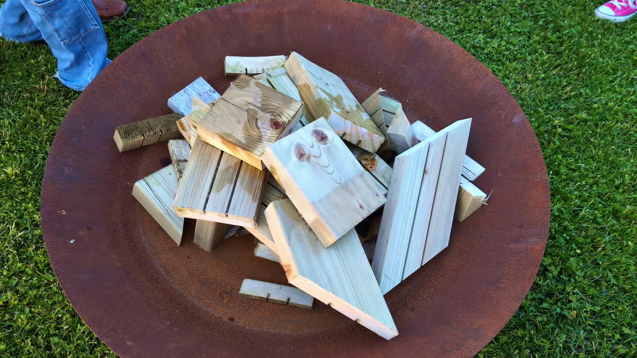 야외에서 위아래로 나무 한 어리로 만든 캠핑 불을 켜고 있습니다.