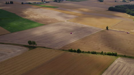 Toma-Aérea-Hacia-Atrás-De-Campos-Agrícolas-Con-Diferentes-Patrones-Y-Colores-Durante-El-Día-Soleado-Con-Sombras-De-Nubes