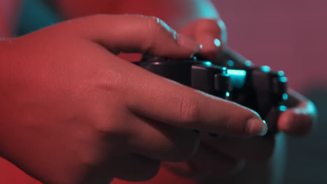 Close-up of women's hands with a game console controller while playing. Colorful lights