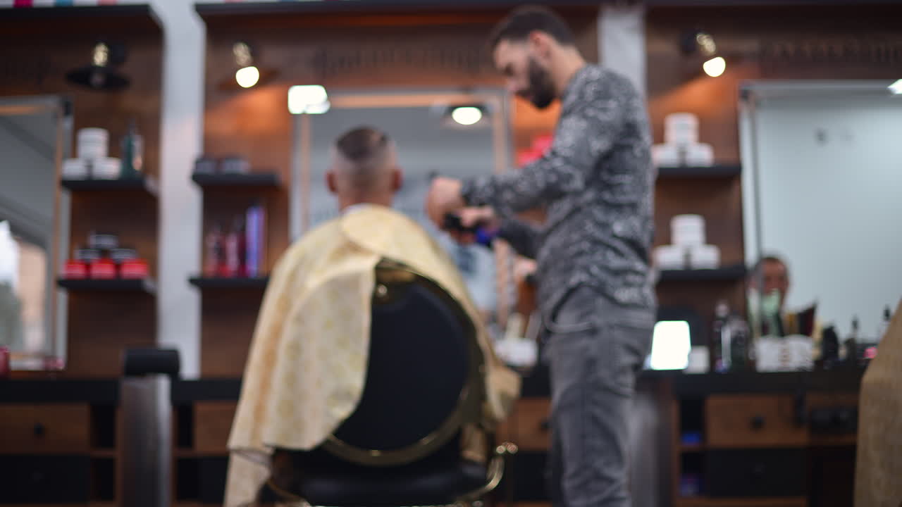 Blurred view of a barber cutting a client's hair inside a modern barbershop