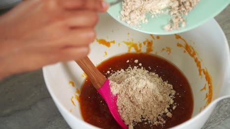 pouring flour in pumpkin batter for vegan pumpkin muffins using real roasted pumpkin in bowl healthy dairy-free recipe vegan