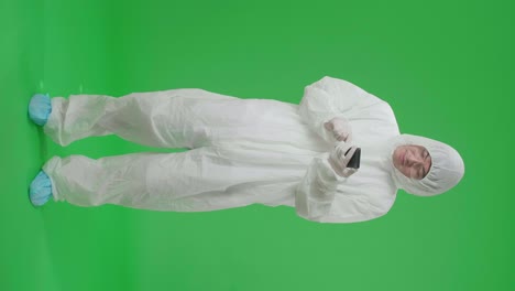 full body of asian man wearing personal protective equipment uniform ppe and use mobile phone then thinking about something, looking around then raising his index finger in the green screen studio