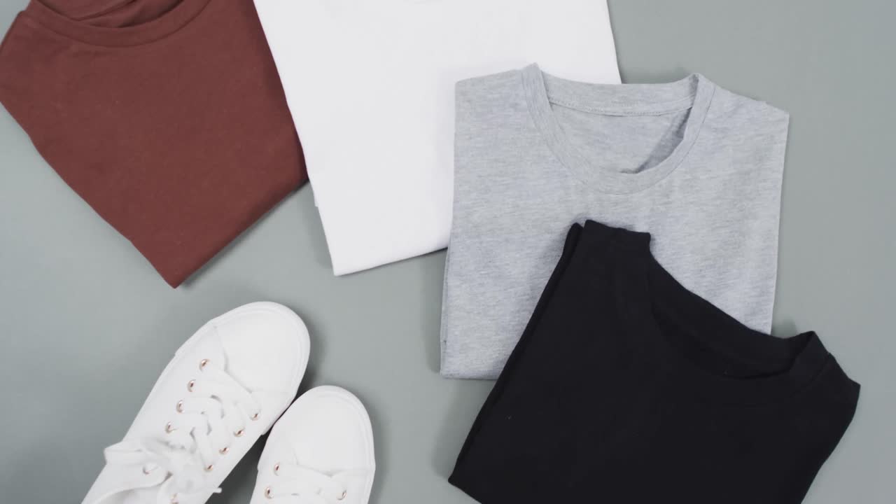 Video of flat lay of t shirts with copy space on grey background