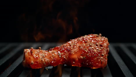 palito de batería marinado cayendo sobre la parrilla en llamas en cámara lenta sobre el fondo negro