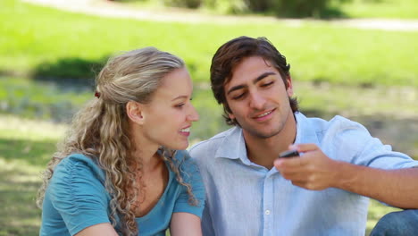 Mujer-Con-Un-Teléfono-Pasándoselo-A-Su-Novio,-Quien-Habla-Y-Luego-Cuelga-Mientras-Miran-Hacia-Adelante.