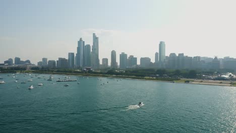 aerial push in towards chicago's grant park as a boat passes through frame