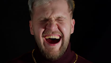 close-up portrait of a man laughing with his hand covering his mouth