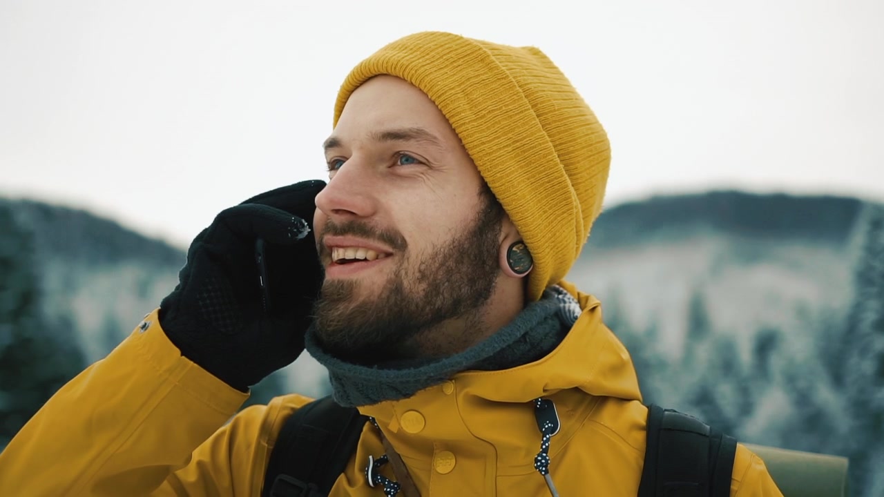 Uomo con giacca gialla che parla al telefono in inverno
