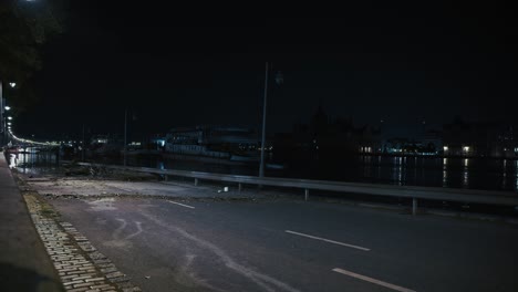 flood debris scattered across a deserted road at night by the river in budapest, hungary