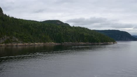 view of mountains from the stern of a ship cruising along saguenay fjord outside of la baie, qc, canada