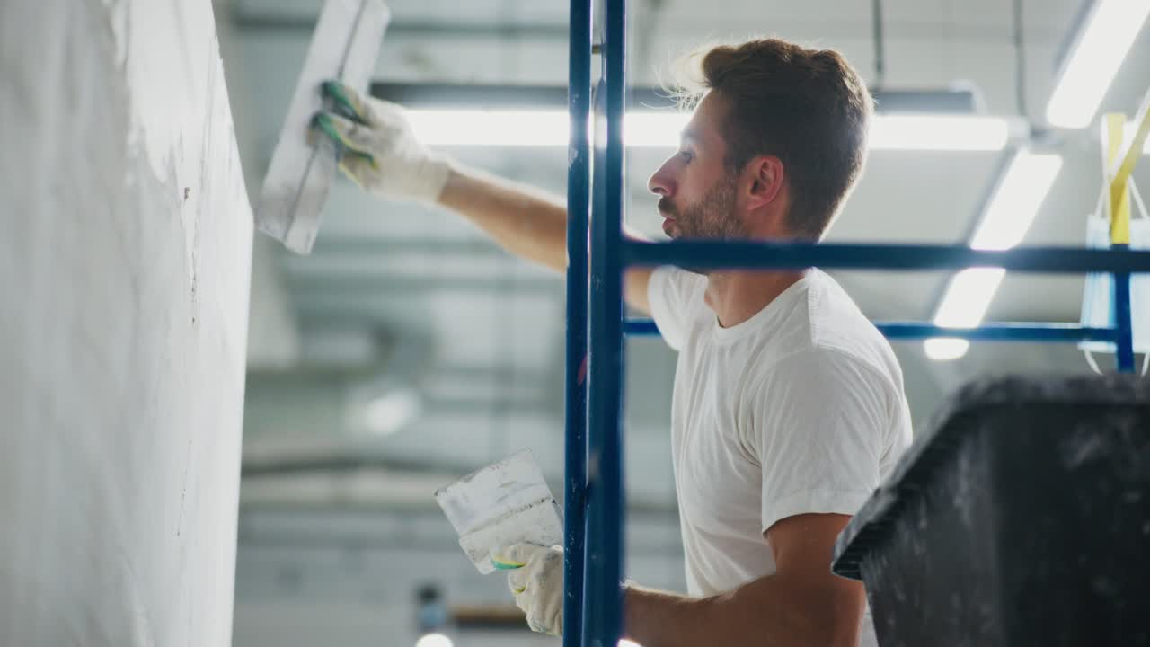 En dedikert arbeider som legger siste hånd på en vegg under innvendig renovering, og viser presisjon og fokus mens verktøy brukes for en jevn overflate