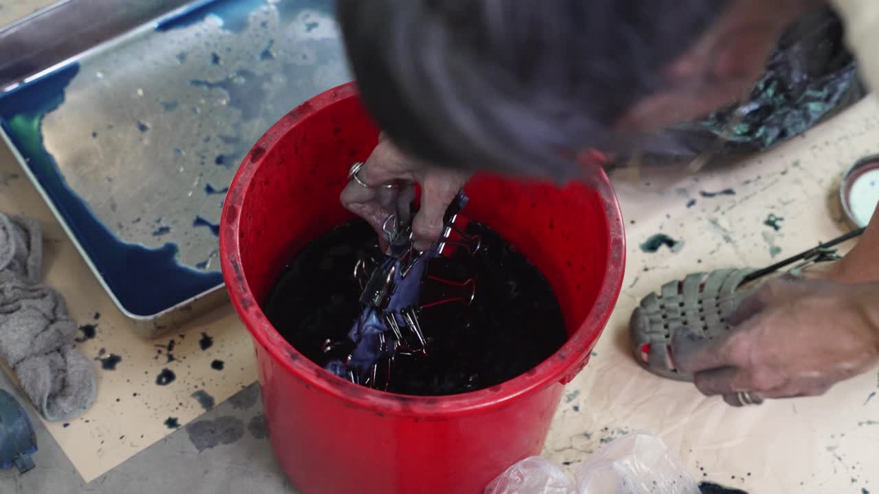 Fabric dye process, stained hands, fluid bucket, traditional technique