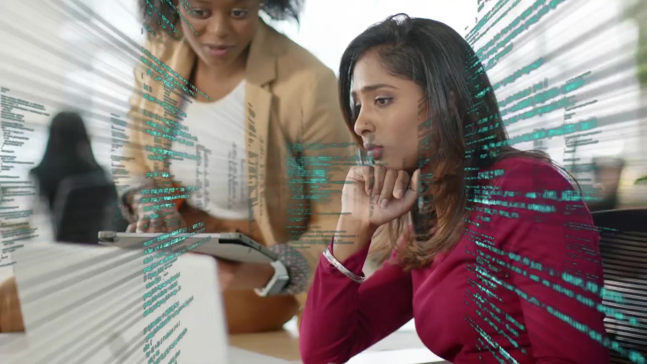 Standing woman scrolling tablet, seated woman leaning forward watching teal code overlay for data