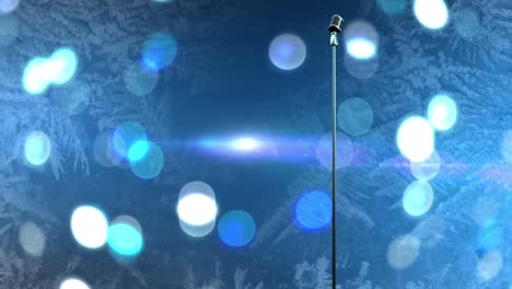 Retro-metallic-microphone-against-spots-of-light-against-blue-background