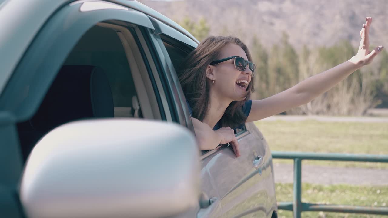 감정적 인 소녀 물결 손이 필드에서 차 밖으로 기울어