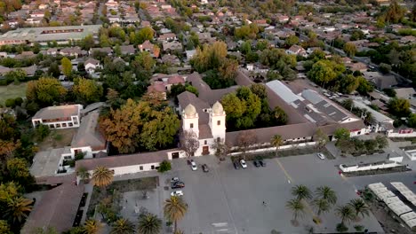 vista aérea de una órbita sobre la iglesia de san vicente ferrer de los dominicos en santiago de chile con sus tejas iluminadas por el sol al atardecer con un barrio residencial - disparo de drones