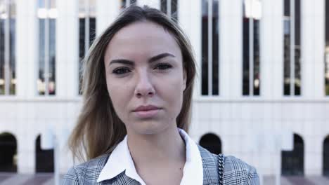 mujer joven emprendedora seria mirando a la cámara en la calle de la ciudad