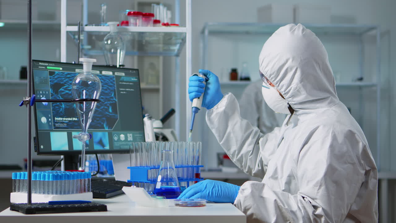 químico con traje de ppe poniendo líquido en un tubo de ensayo con una micropipeta