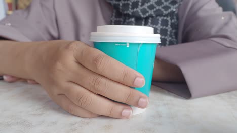 woman holding a teal coffee cup